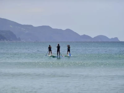 沖でSUPをする3人の人